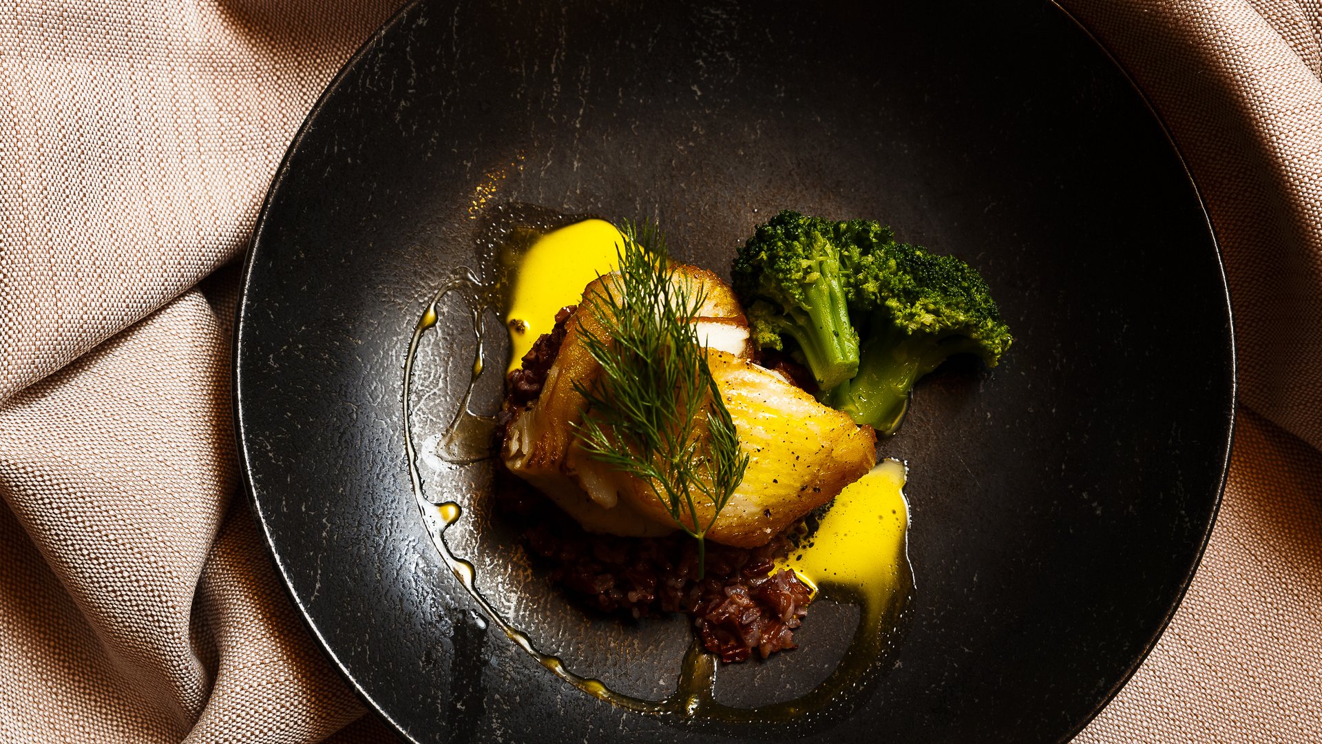 Sich erholen im Hotel in Neustift im Stubaital Gebratenes Fischfilet mit Brokkoli und Sauce auf schwarzem Teller