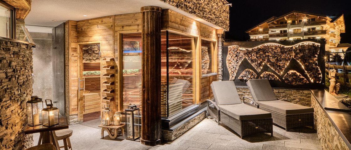 Sich erholen im Hotel in Neustift im Stubaital Beleuchtete Terrasse mit Saunaraum und Liegestühlen in Berghotel bei Nacht