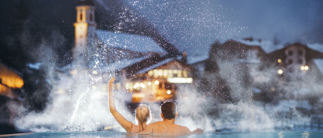 Sich erholen im Hotel in Neustift im Stubaital Paar entspannt im beheizten Außenpool bei Winterabend im Alpenort