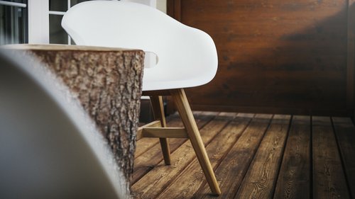 Sich erholen im Hotel in Neustift im Stubaital Weißer Stuhl mit Holzbeinen auf Holzboden neben Baumstumpf-Tisch