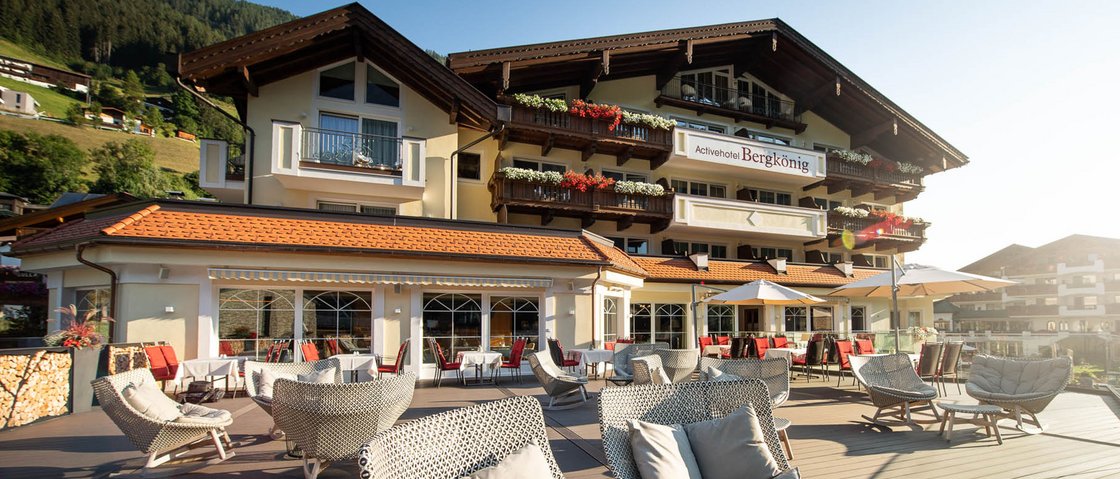 Sich erholen im Hotel in Neustift im Stubaital Terrasse mit Sitzgelegenheiten vor Alpine Hotel in sonniger Berglandschaft